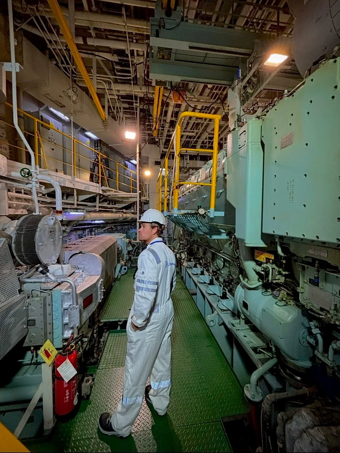 Marine engineer inspecting machinery and pipework inside a vessel engine room