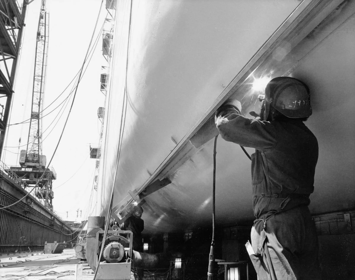 Certified welder carrying out steel repair work on a ship hull in dry dock
